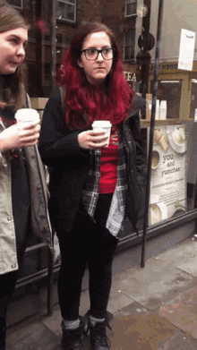 a girl with red hair is holding a cup of coffee in front of a store that sells you and yumchas