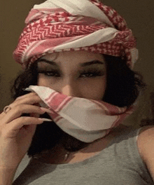 a woman is wearing a scarf around her face and covering her mouth .