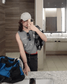 a man taking a picture of himself in a bathroom with a bag on the counter