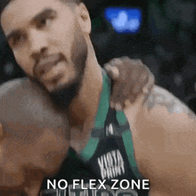 a basketball player is hugging another player with the words no flex zone on the bottom .