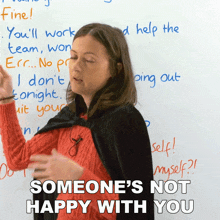 a woman stands in front of a white board with the words " someone 's not happy with you "