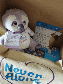 a stuffed animal in a box with a never alone shirt