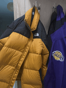 a north face jacket hangs next to a purple lakers jacket