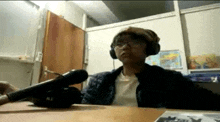 a person wearing headphones and a hat is sitting at a desk with a microphone .