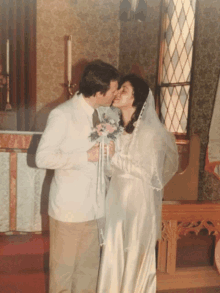 a bride and groom kissing on their wedding day in a church