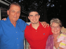 a man in a red shirt with an eagle on it poses with two older men