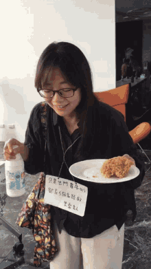 a woman wearing glasses holds a plate of food and a sign that says ' a fried chicken ' on it