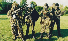 a group of soldiers are standing in a grassy field holding guns