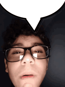 a boy wearing glasses has a speech bubble over his head