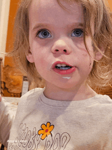 a little girl wearing a shirt with a flower on it has a dirty face