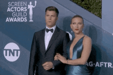 a man and a woman are standing on a red carpet with the screen actors guild awards in the background