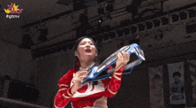 a woman in a red and white outfit is holding a trophy with the hashtag #gtmv on the bottom right