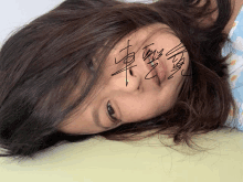 a woman with chinese writing on her face laying down