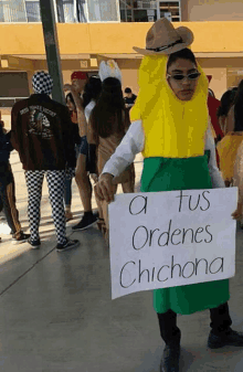 a man in a banana costume is holding a sign that says tus ordenes chichona