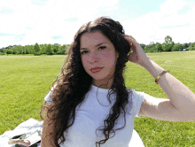 a woman with curly hair is sitting in a field