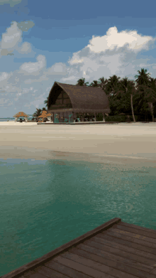 a thatched building sits on a sandy beach near the ocean