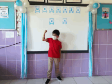 a boy wearing a mask stands in front of a white board that says merhab