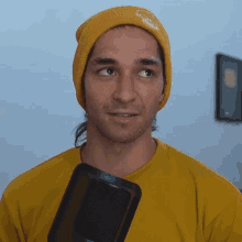 a man wearing a yellow beanie holds a microphone