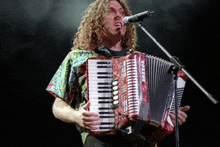 a man singing into a microphone while playing an accordion that says hohner