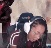 a woman wearing headphones and glasses sits in a gaming chair with the number 12 on the bottom