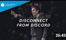 a man in a suit and tie is standing in front of a crowd and is talking about disconnecting from discord