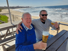 two men are sitting at a table with a glass of budweiser