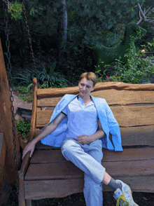 a man sits on a wooden bench with a blue jacket on