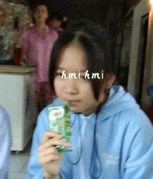 a girl in a blue jacket drinking milo from a box