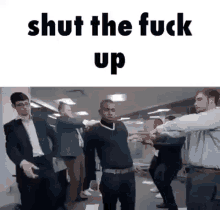 a group of men are dancing in an office with the words `` shut the fuck up '' written on the bottom .