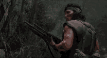 a man is holding a shotgun in the woods