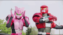 a pink robot and a red robot are posing for a picture