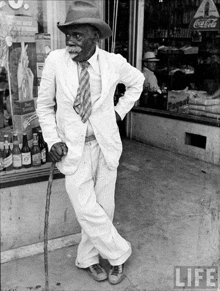 a man with a cane stands in front of a store with a coca cola sign