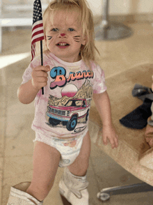 a little girl wearing a shirt that says bravo holding an american flag