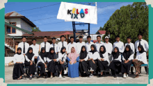 a group of people posing for a photo with a sign that says kelas