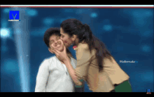 a woman kisses a child on the cheek on a television screen that says mallemala