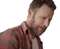 a man with a beard wearing a plaid shirt looks down