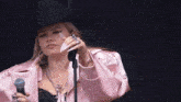 a woman wearing a cowboy hat is singing into a microphone