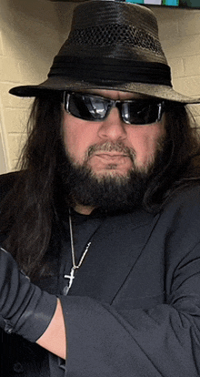 a man with long hair and a beard wears a hat and sunglasses