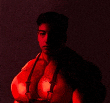 a man with a tattoo on his chest is standing in a dark room