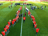 a group of people standing in a circle on a soccer field with a man wearing a red shirt with the number 8 on it