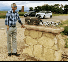 a man stands in front of a mailbox that has a horse drawn carriage on it