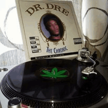 a record player with a marijuana leaf on it and a dr. dre album on top of it .