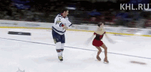 a man and a woman are ice skating on a rink . the woman is wearing a red dress .