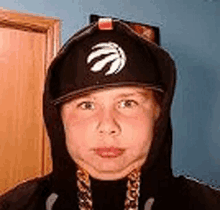 a young boy wearing a toronto raptors hat and a hoodie .