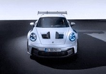 a white porsche 911 gt3 rs is parked on a black surface .