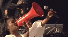 a woman is holding a red megaphone in her mouth .