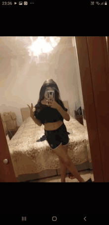 a woman is taking a selfie in front of a mirror with the time of 23:36