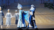 a woman in a blue and white dress is dancing with a man in a blue and white costume