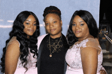 three women are posing for a picture and one of them has a gold necklace