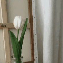 a white flower in a glass vase next to a wooden frame with the number 10 on it